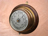 Ships bulkhead barometer with silvered aluminium dial and carries the name John Barker & Co Ltd, Kensington